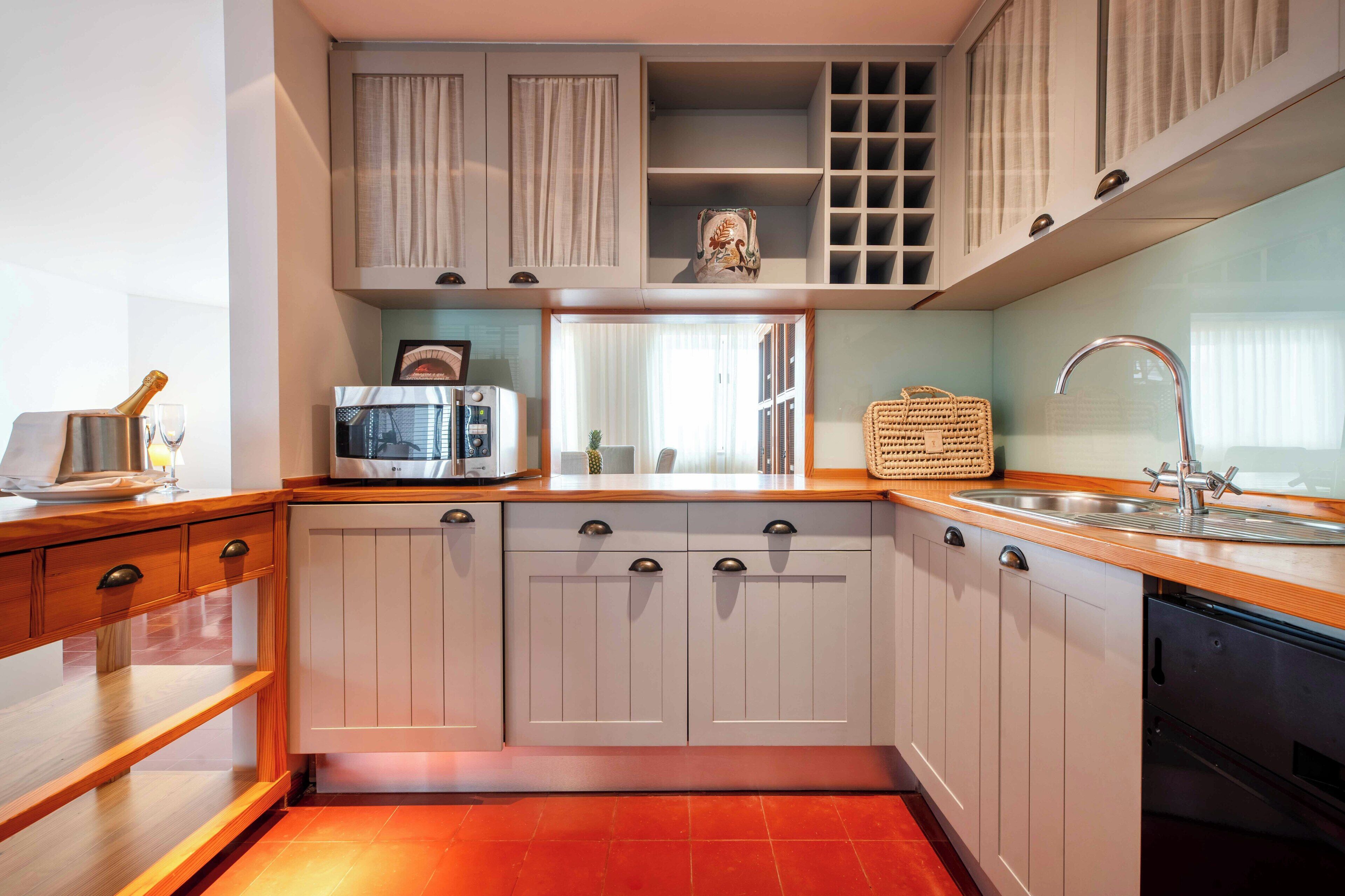 A kitchen with white cabinets, a microwave, a toaster, and a sink.