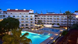 A hotel with a swimming pool, multiple balconies, and a red-roofed building in the background. - Aqualuz Lagos by The Editory (Lagos)
