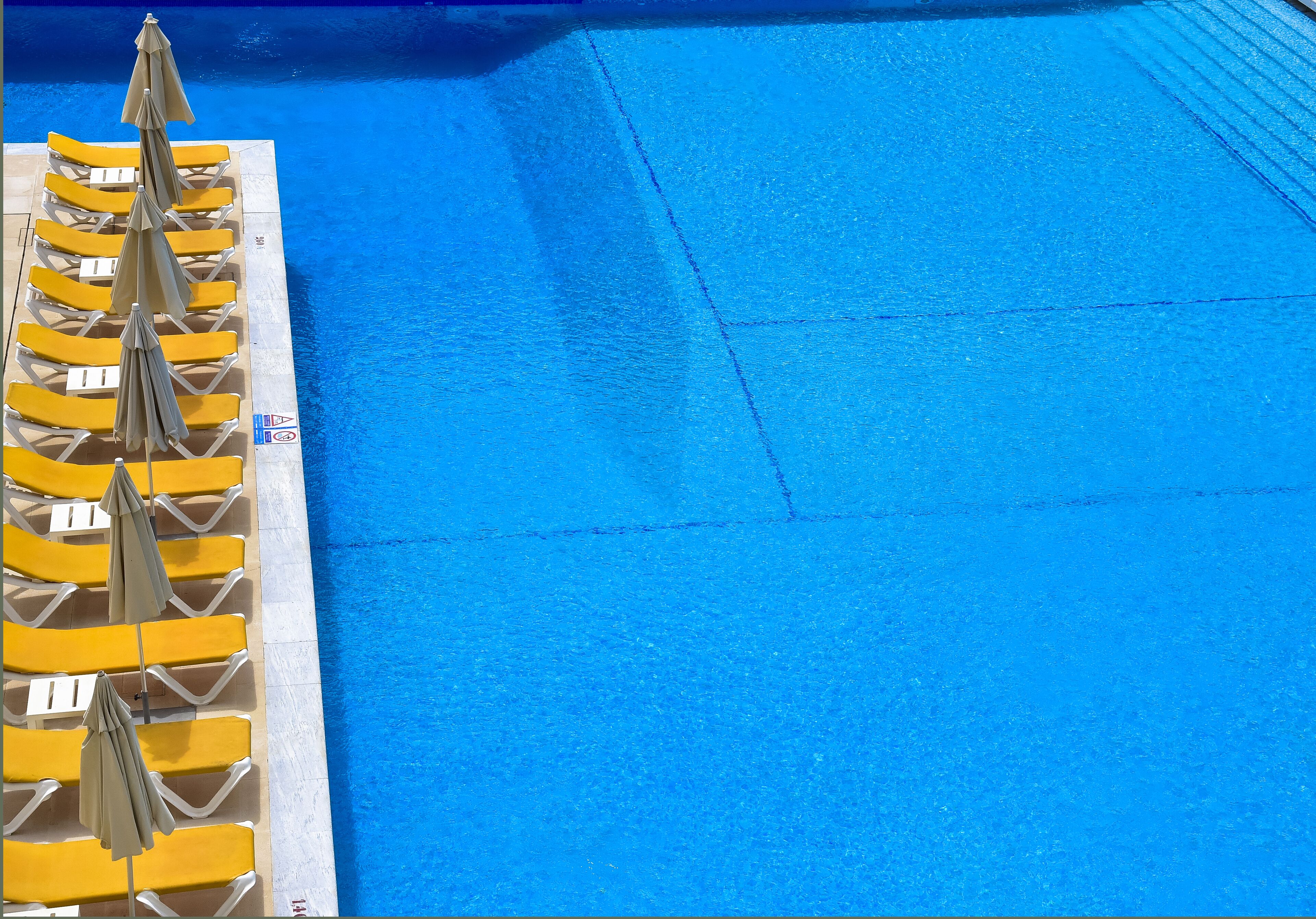 A poolside area with yellow lounge chairs and umbrellas.