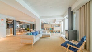 A spacious living area with a sofa, a reading chair, a bookshelf, and a television. - Aqualuz Lagos by The Editory (Lagos)