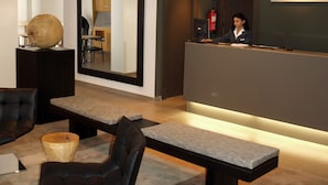Uma área de recepção moderna, com balcão, espaço de estar e um espelho grande.