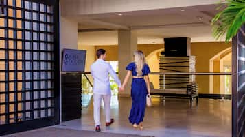 A couple walking through the entrance of a hotel with a sign that reads "Casa Dorada."