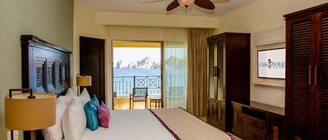 Habitación de hotel con cama, ventilador de techo, televisión y vista al mar.