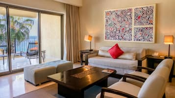 A hotel room with a balcony, a sofa, a coffee table, and a large abstract painting on the wall.