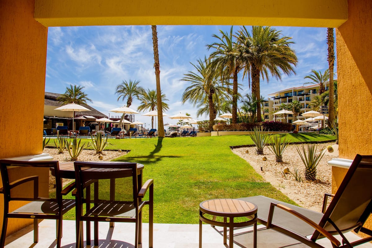A resort patio with outdoor seating, palm trees, and a pool area.