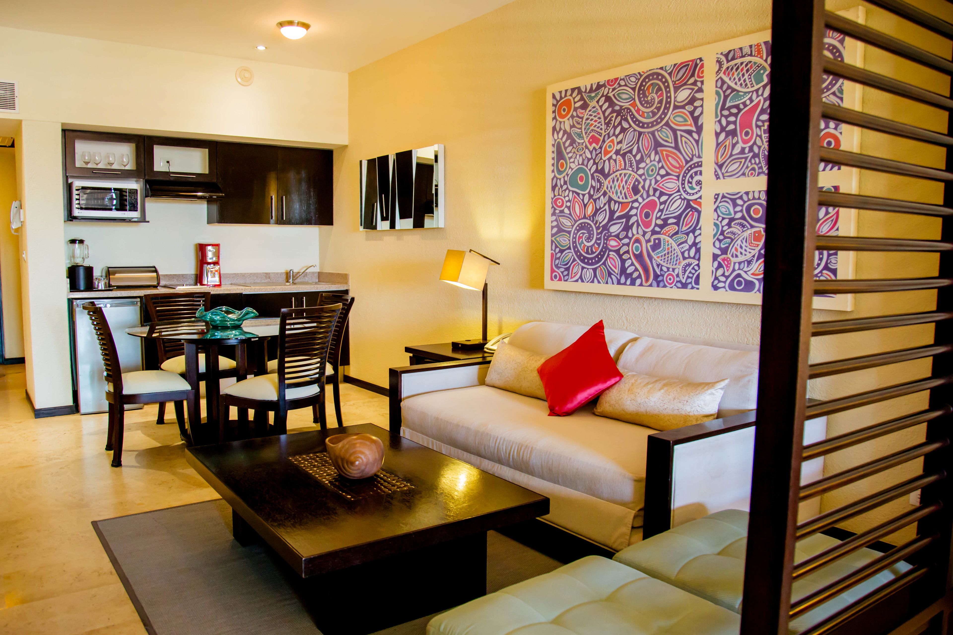 A modern living room with a sofa, coffee table, and dining area with chairs and a table.