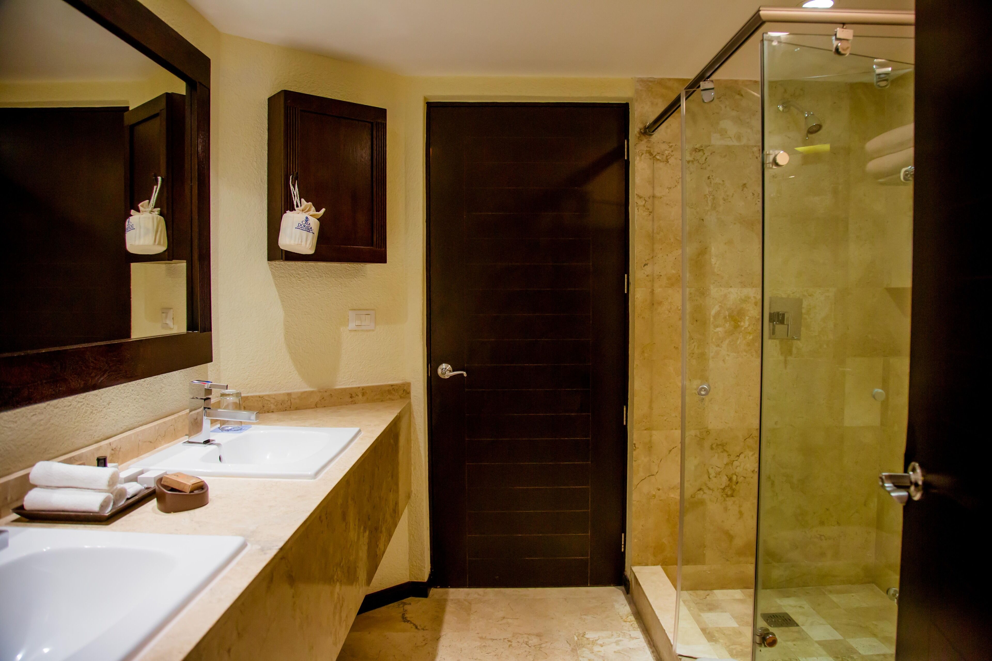 A bathroom with two sinks, a mirror, a shower, and a door.