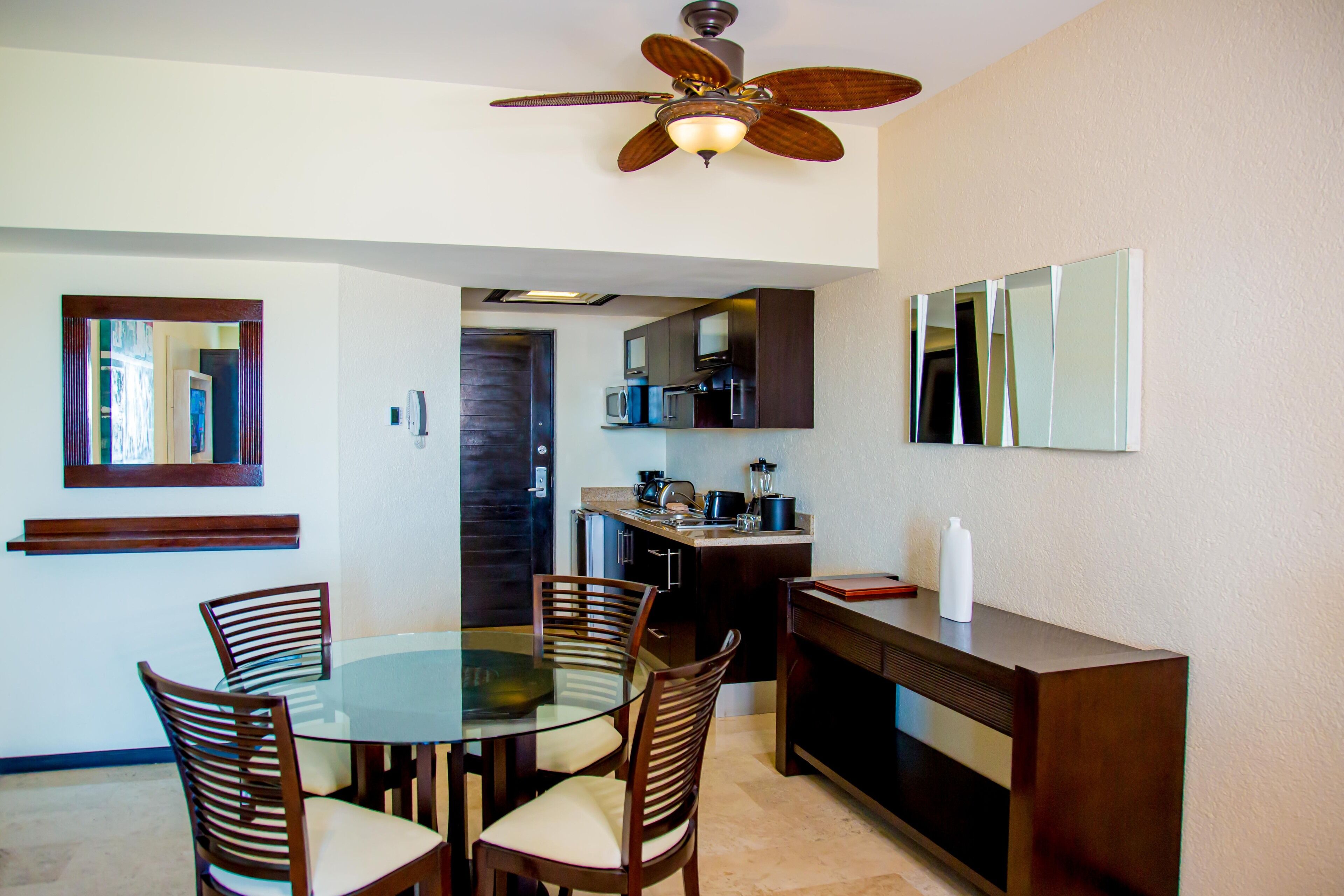 A compact kitchen with a dining area, a ceiling fan, and a microwave.
