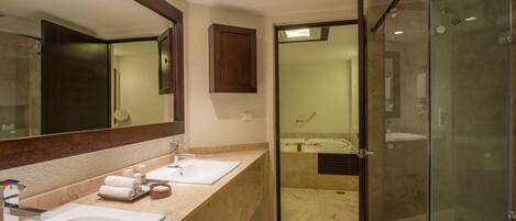 A hotel bathroom with two sinks, a large mirror, and a glass-enclosed shower area.