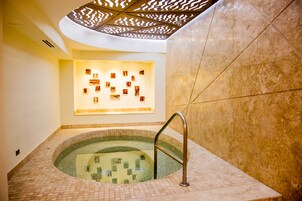 Un área de spa con un jacuzzi con azulejos, un pasamanos de metal y una pared con cuadros enmarcados.