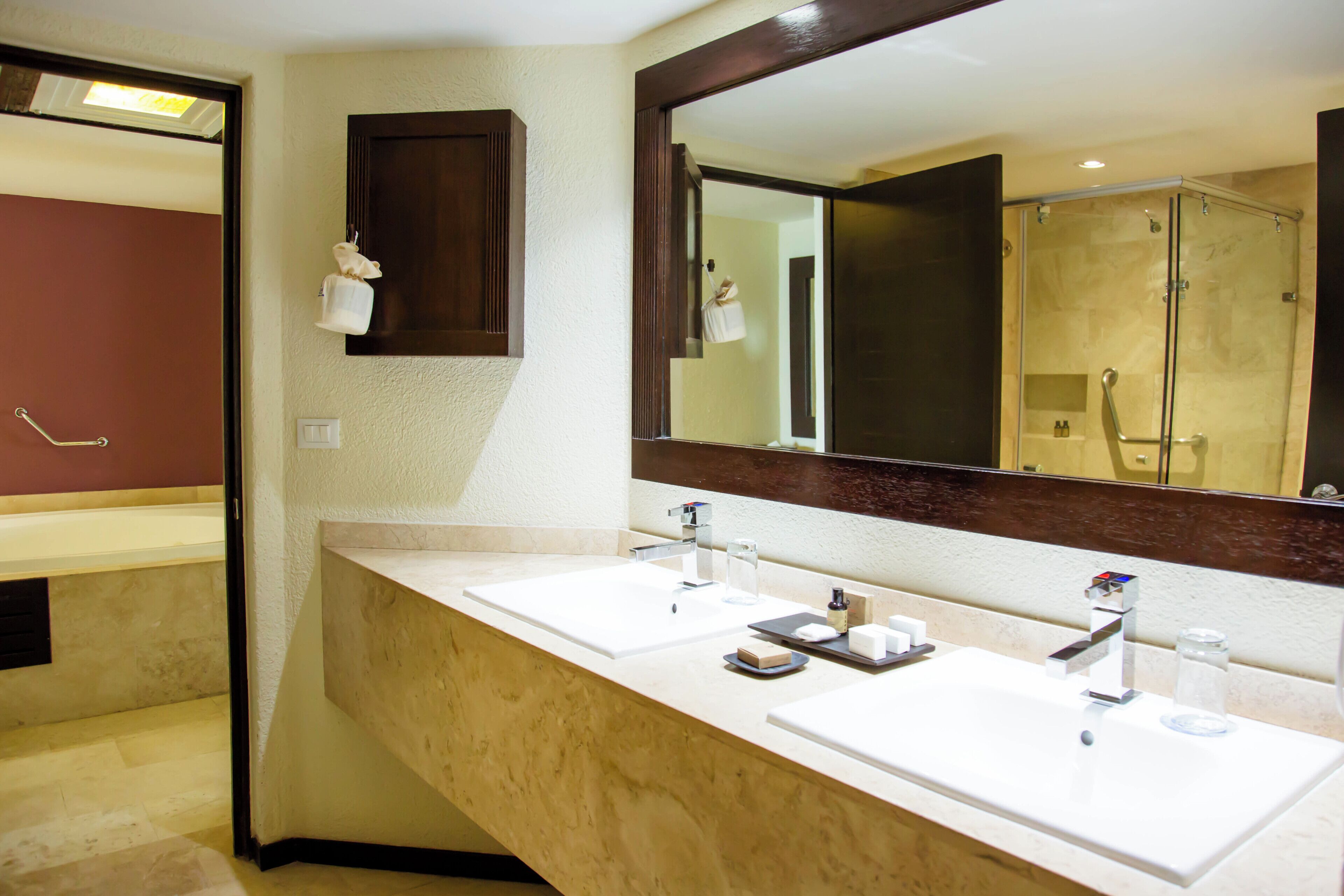 Une salle de bain avec deux lavabos, un grand miroir et un espace douche.
