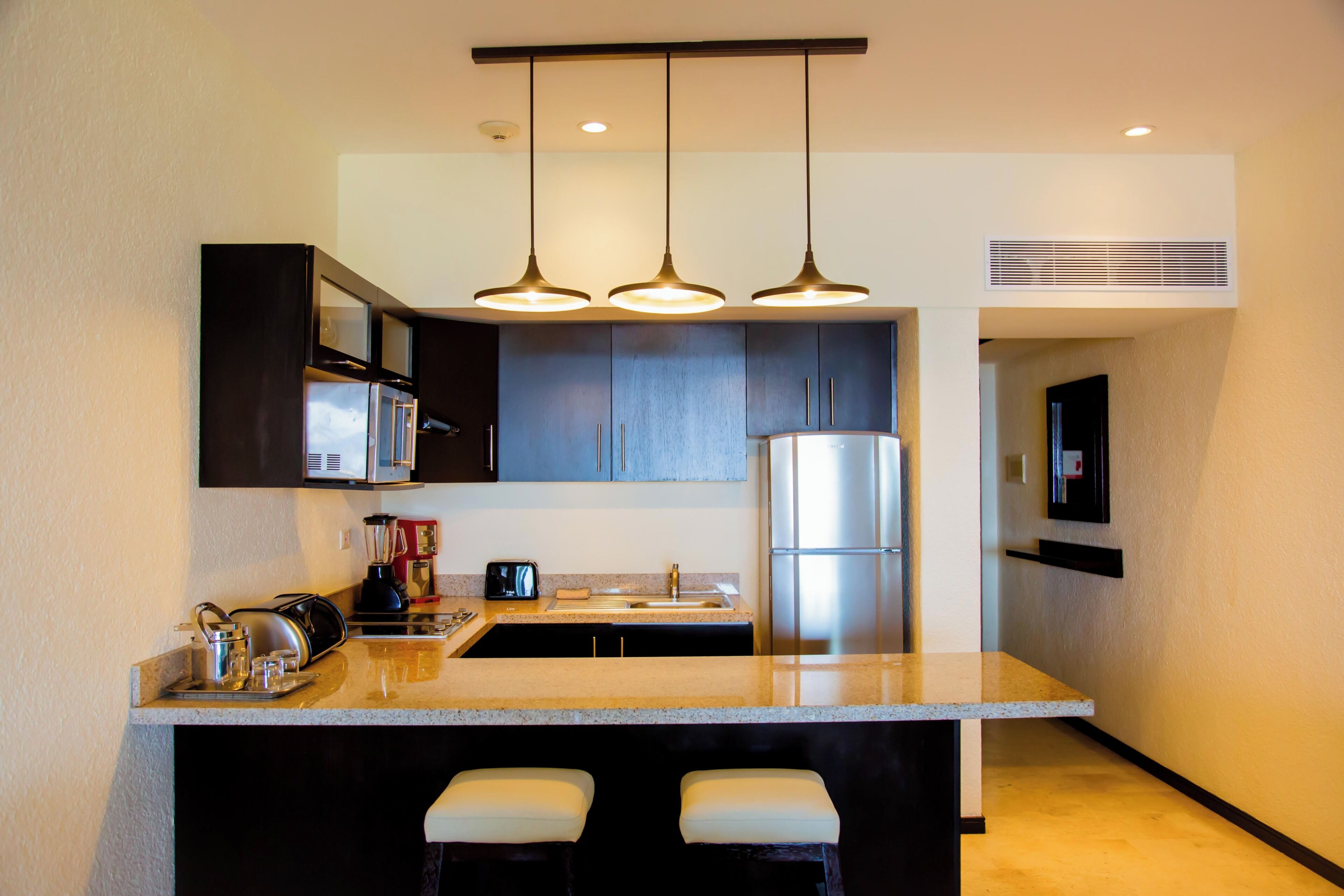 A modern kitchen with a central island, stainless steel appliances, and pendant lighting.