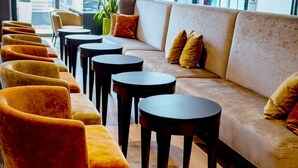 A modern lounge area with a sofa and chairs, small tables, and large windows. - Caravelle Hotel im Park (Bad Kreuznach)
