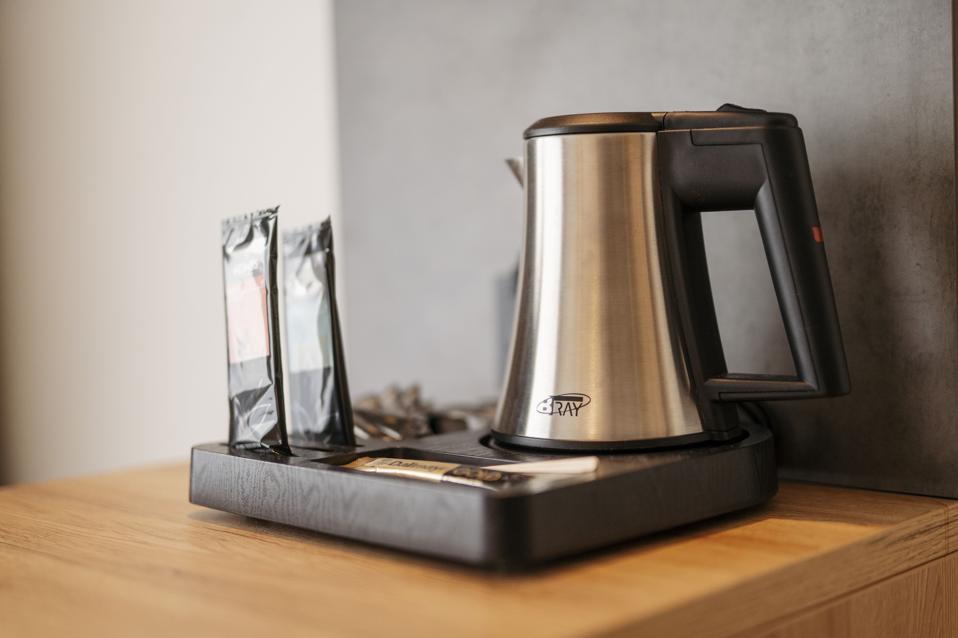 A coffee maker with a black handle and a metallic body on a wooden surface.