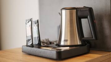 A coffee maker with a black handle and a metallic body on a wooden surface.