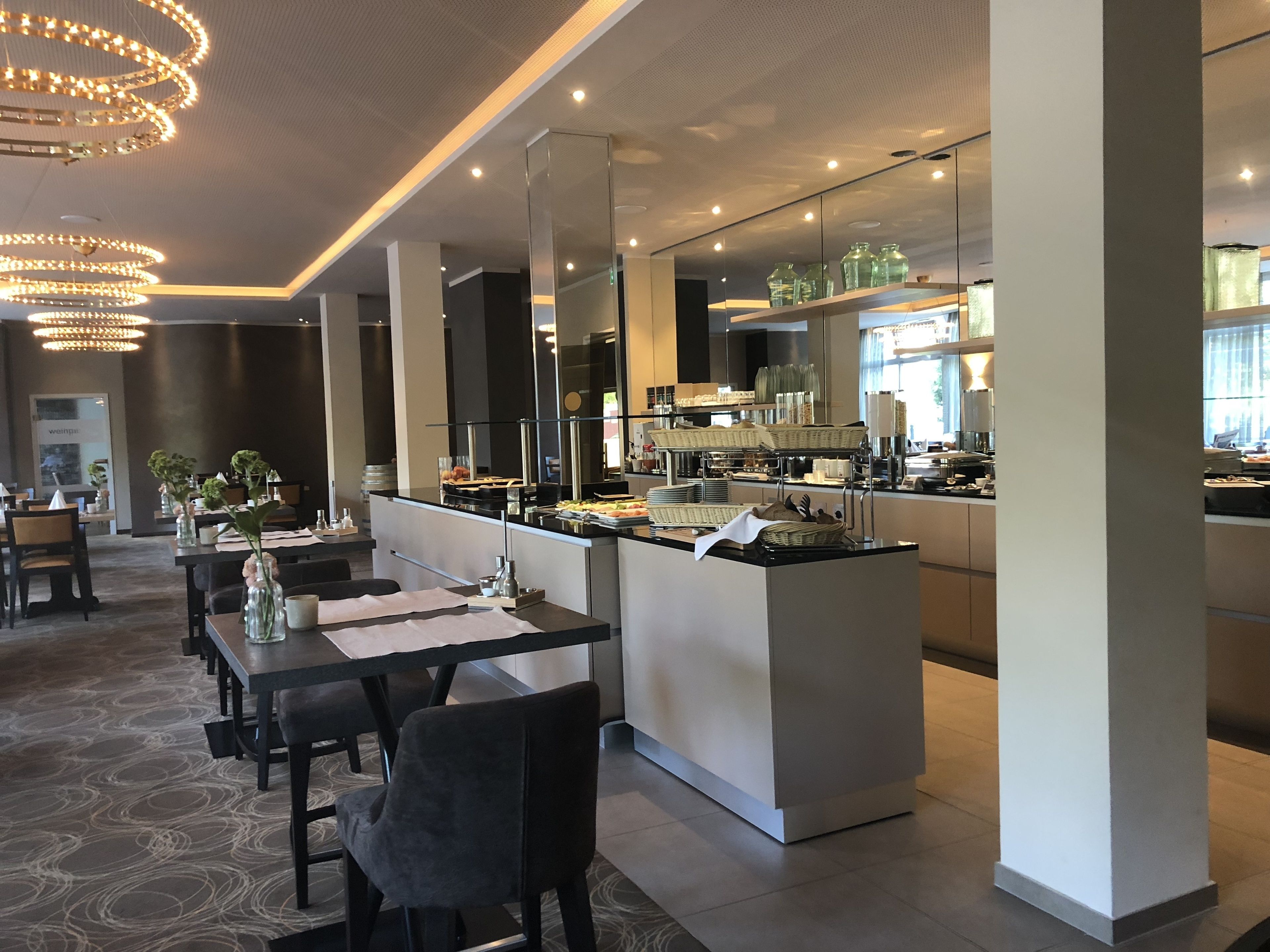 Ein modernes Restaurant mit einer zentralen Kochinsel, Esstischen und Stühlen.