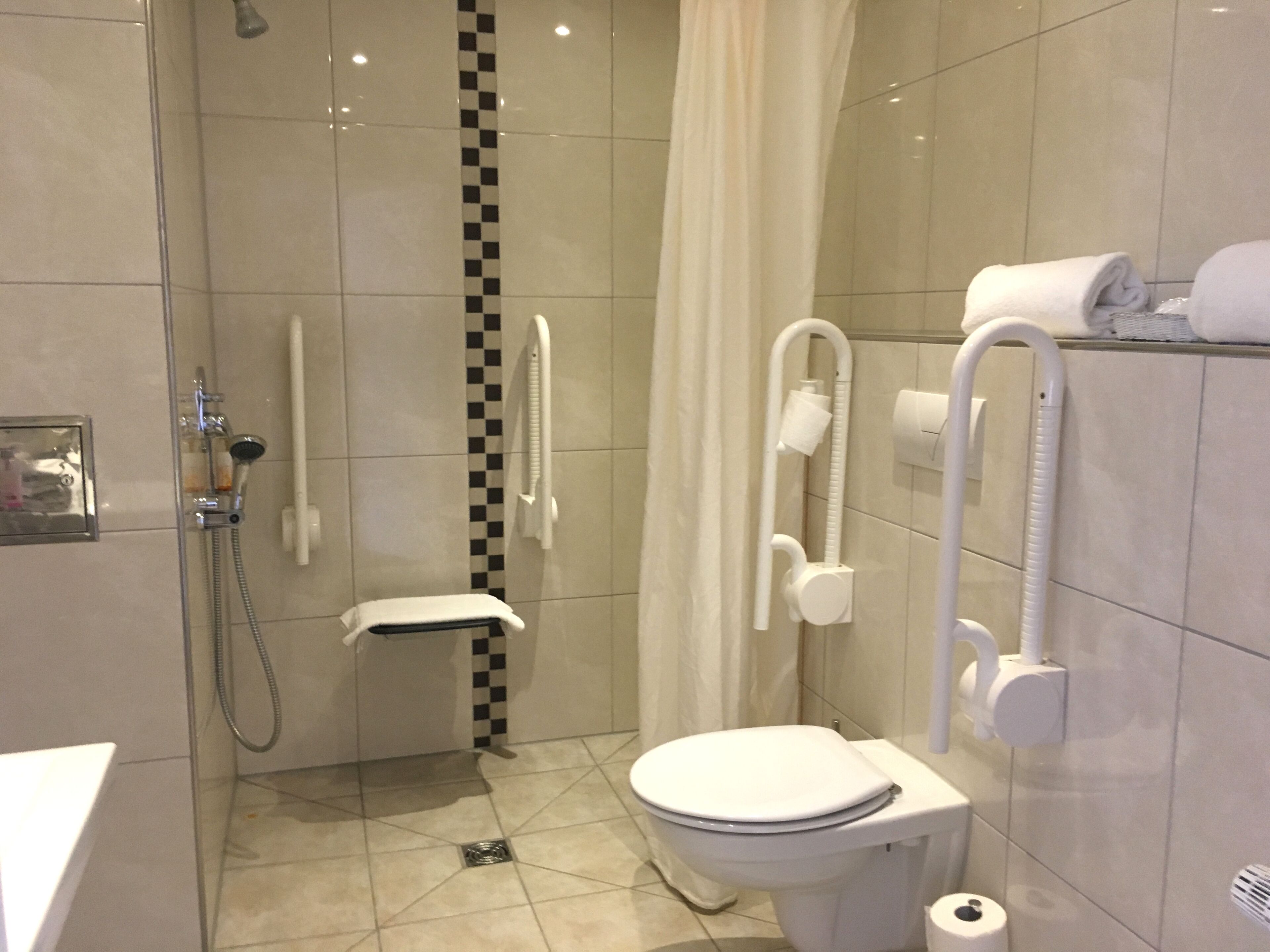 A modern bathroom with a glass-enclosed shower, a toilet with a white seat, and a towel rack with towels.