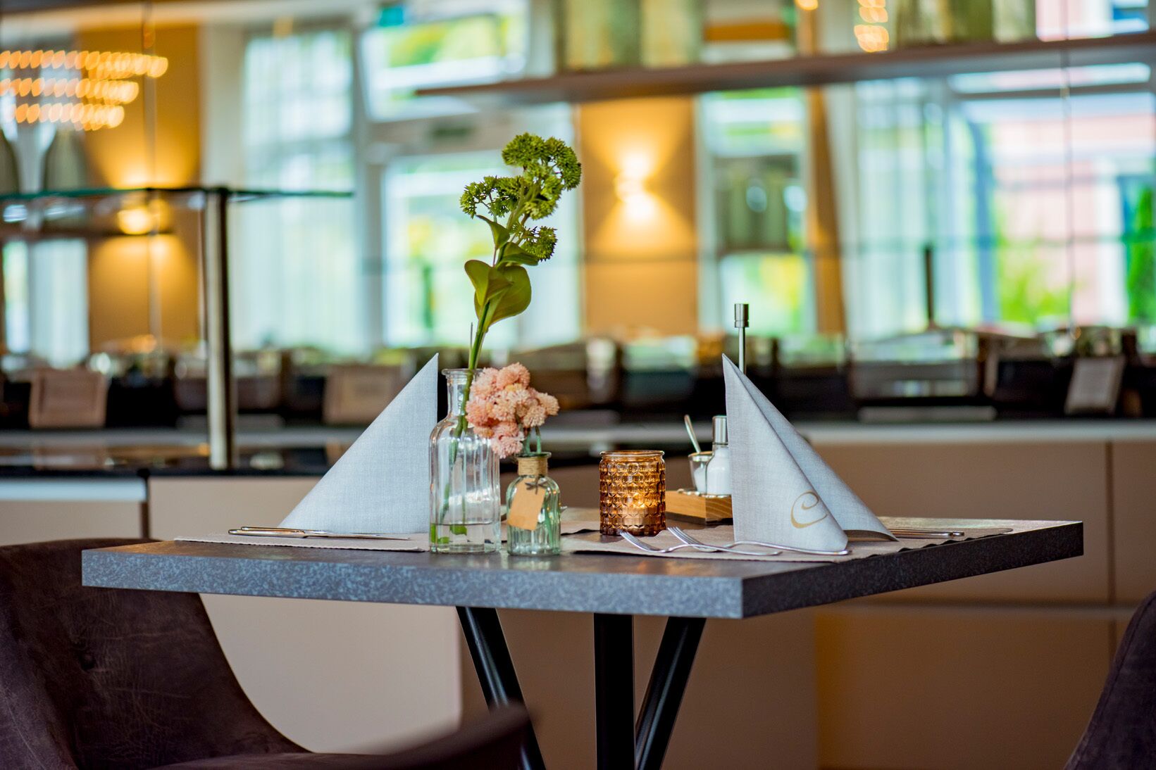 A dining table set with a vase of flowers, a candle, and a napkin holder.