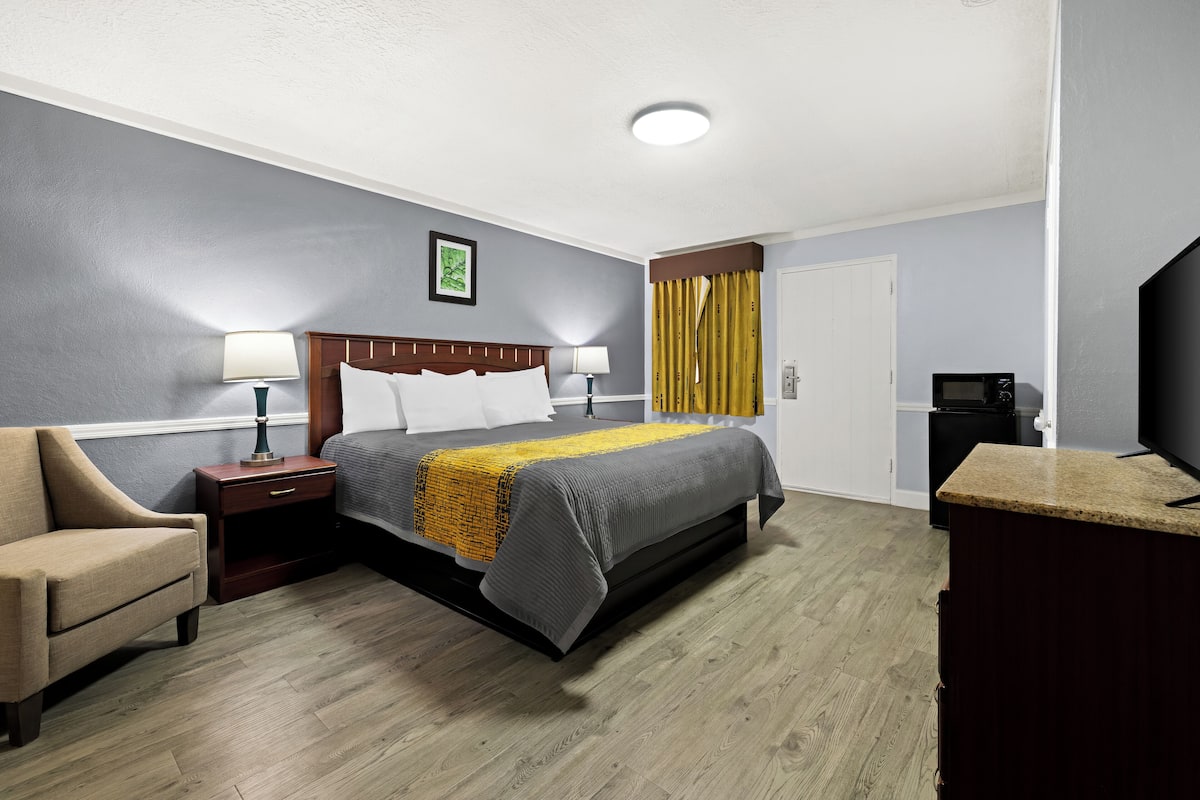 Une chambre d’hôtel équipée d’un lit, de tables de chevet, d’une chaise, d’un bureau, d’une télévision et d’un four à micro-ondes.