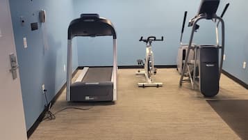 A room with a treadmill, stationary bike, and elliptical machine.