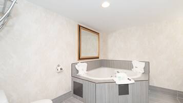 A modern bathroom with a freestanding bathtub, a toilet, and a mirror on the wall.