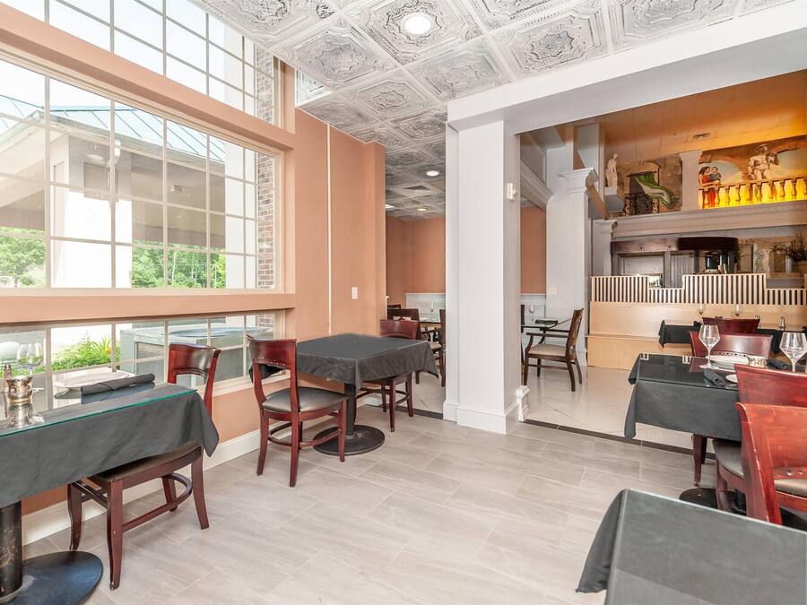 A dining area with tables and chairs, large windows, and a decorative ceiling.