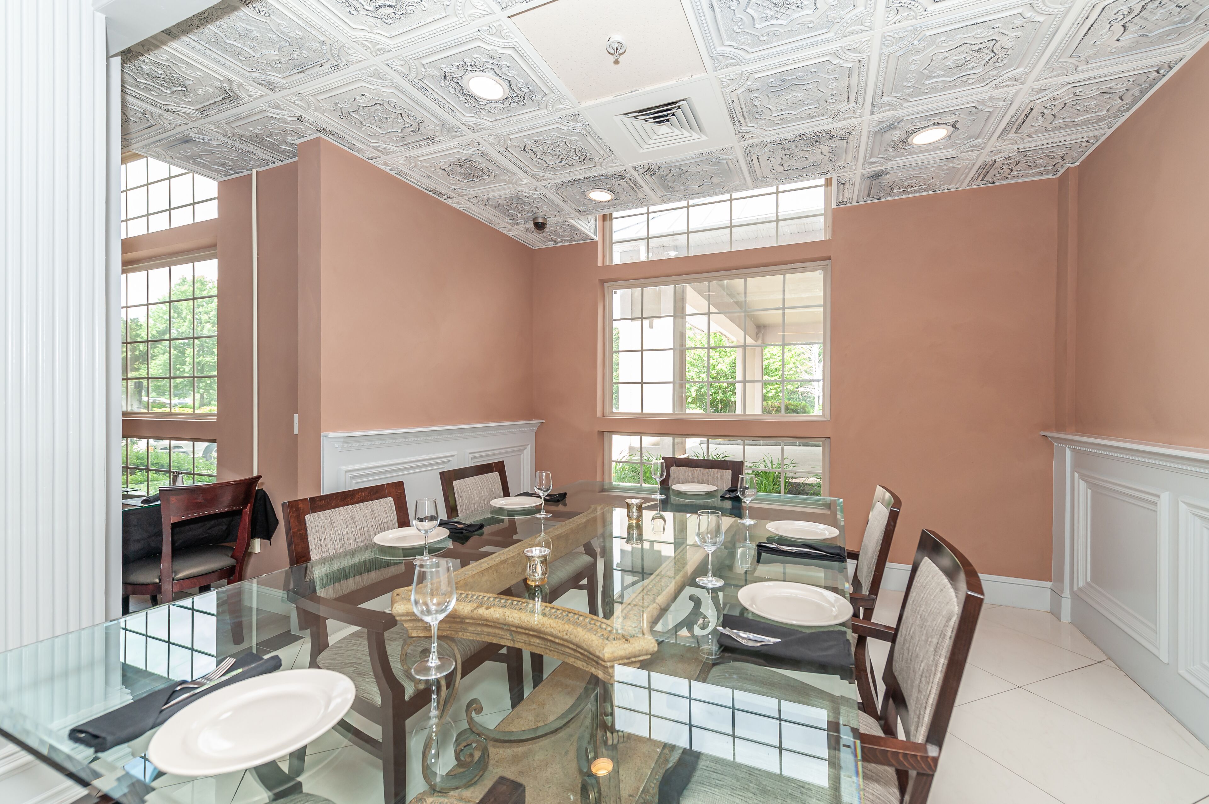 A dining room with a glass table, chairs, and a decorative ceiling.