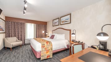 A hotel room with a bed, a desk, a chair, a nightstand, a lamp, and a window with curtains.