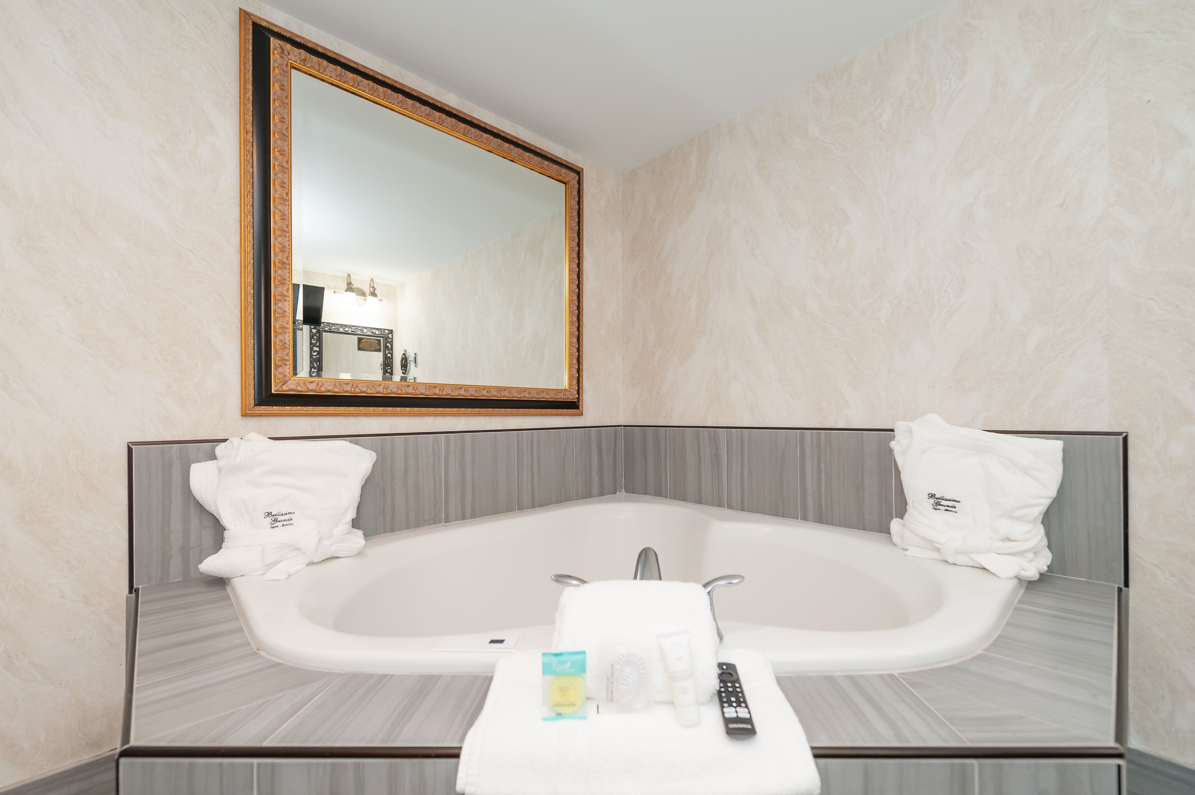 A modern bathroom with a freestanding bathtub, a large mirror, and two towels on the wall.