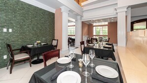 A dining area with multiple tables set for service, a brick wall, and a view of the outdoors. - Bellissimo Hotel, Trademark by Wyndham Near Foxwoods Casino (North Stonington)