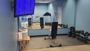 A gym with exercise equipment, a mirror, a television, and a water dispenser.