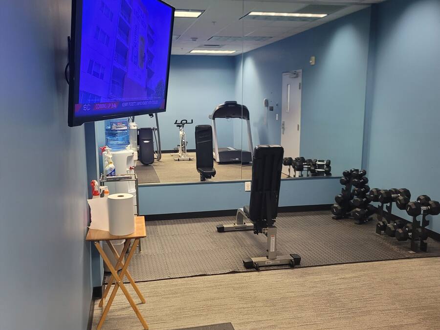A gym with exercise equipment, a mirror, a television, and a water dispenser.