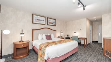 A hotel room with a bed, bedside tables, a desk, and a chair. There are two framed pictures on the wall above the bed.