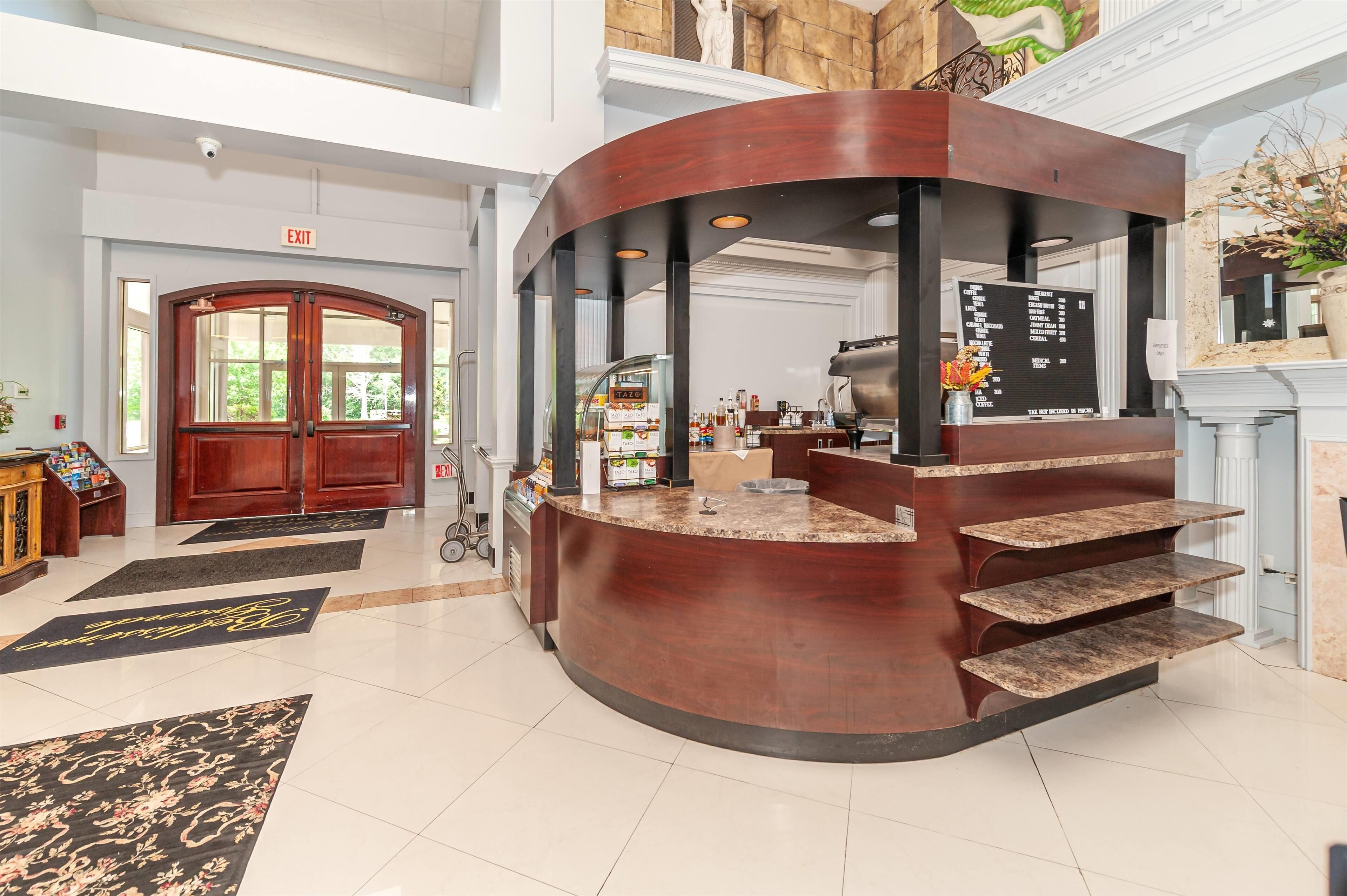A lobby with a curved reception desk, a staircase, and a large stone fireplace.