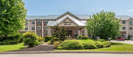 A hotel with a prominent entrance and a landscaped front yard.