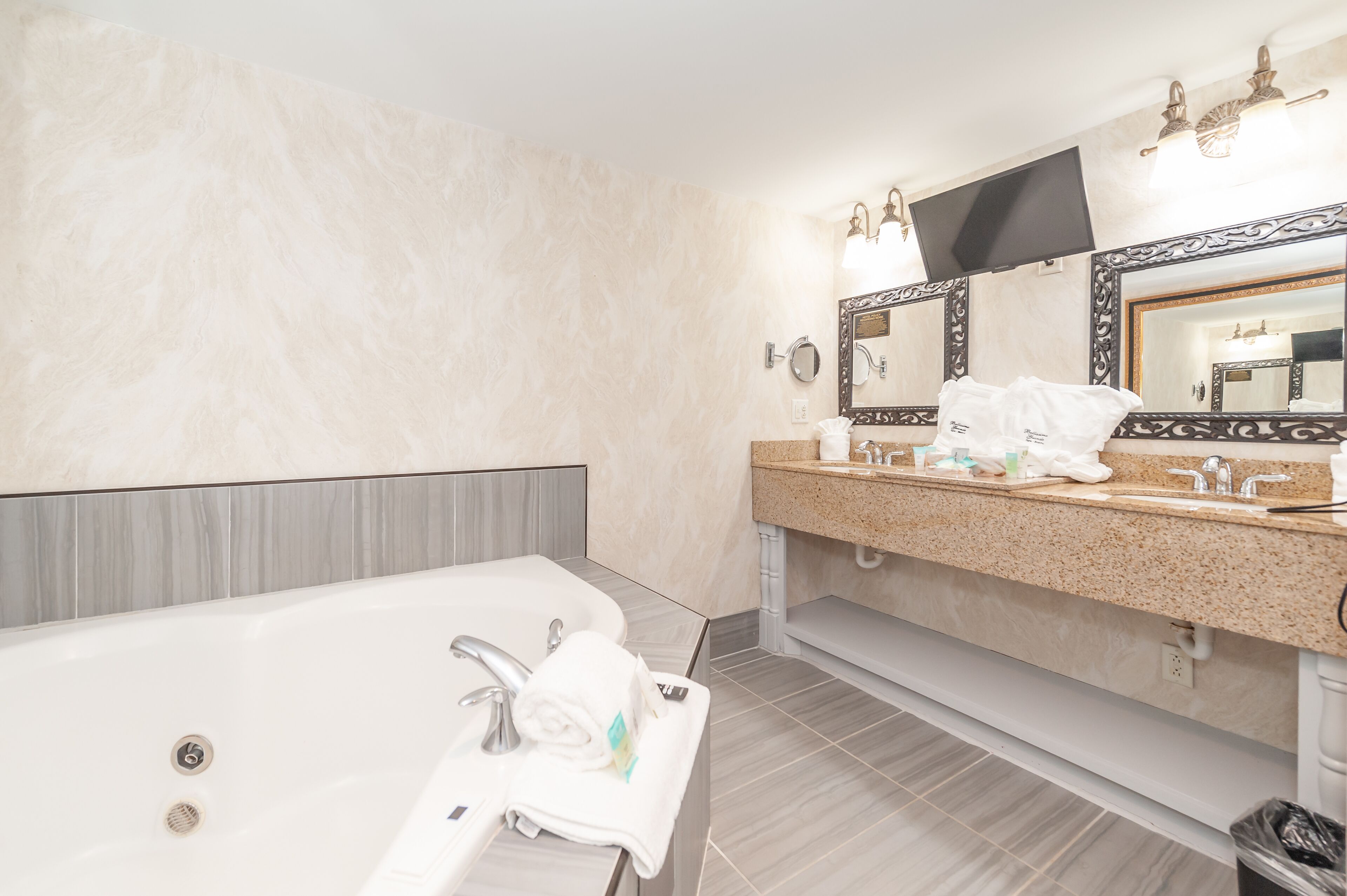 A modern bathroom with a large bathtub, a vanity with a mirror, and a towel rack.