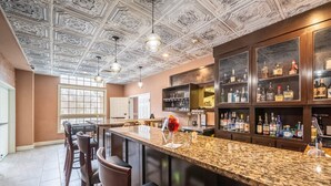 A bar area with a granite countertop, bar stools, and a ceiling with intricate designs. - Bellissimo Hotel, Trademark by Wyndham Near Foxwoods Casino (North Stonington)