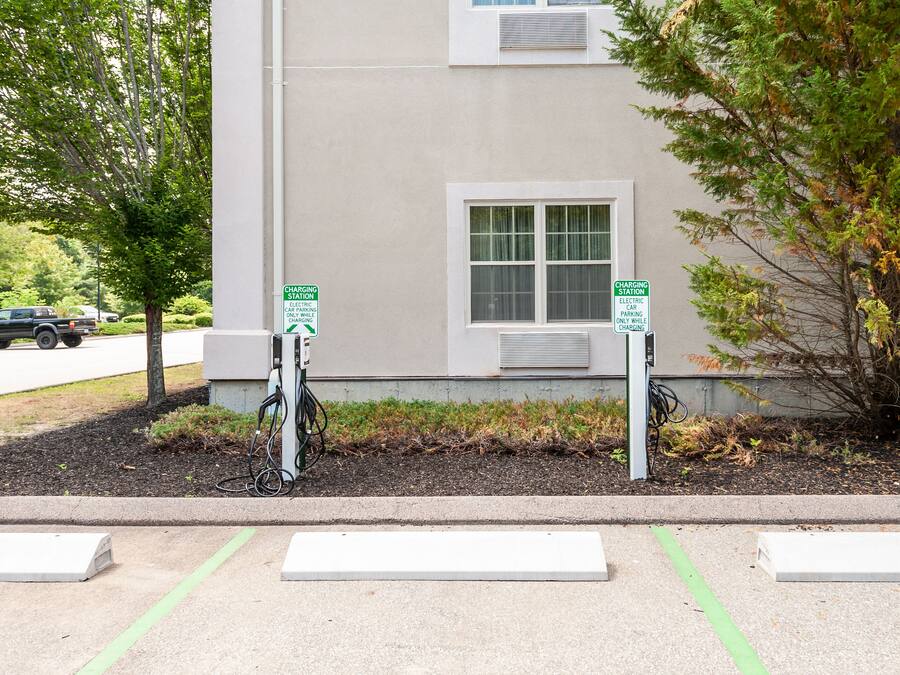 A building with two charging stations for electric vehicles, a window, and a sidewalk with a curb.