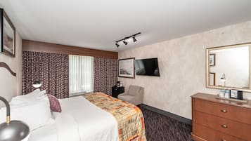 Habitación de hotel con cama, escritorio, silla, cómoda y televisión.