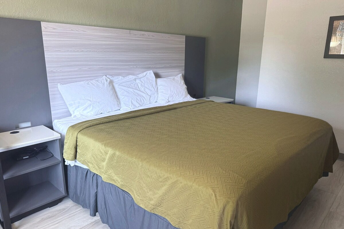 Una habitación de hotel con una cama, una mesita de noche y una mesilla.