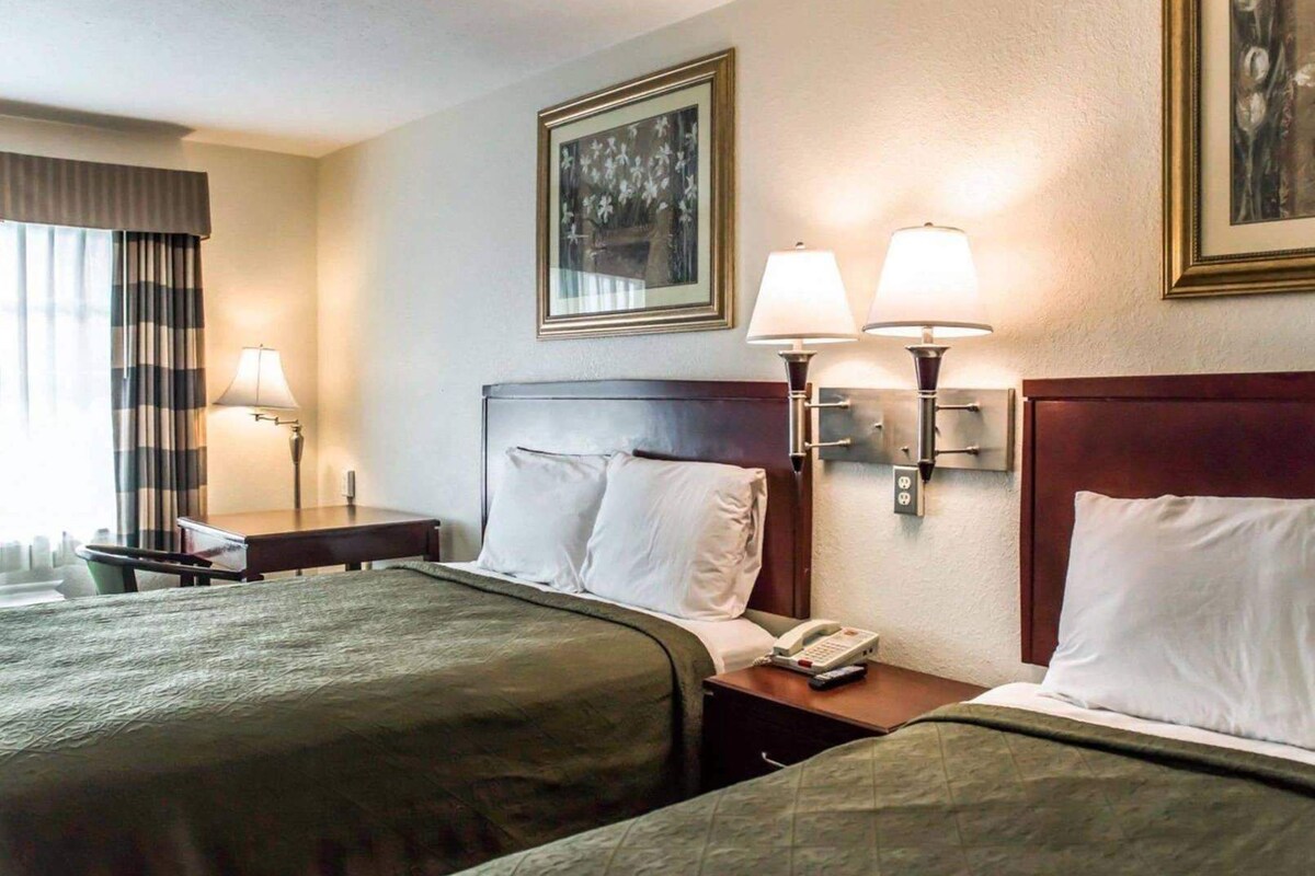 Habitación de hotel con dos camas, una mesita de noche con teléfono y lámparas fijadas a la pared.