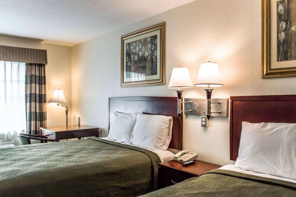 Habitación de hotel con dos camas, una mesita de noche, un teléfono y lámparas fijadas a la pared.