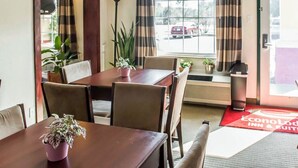 A hotel room with a dining table, chairs, a potted plant, a window with curtains, and a view of the outside parking area. - Econo Lodge Monticello (Monticello)