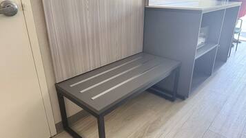 A bench with a metal frame and slatted seat, positioned next to a door and a counter.