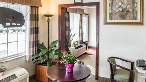 A hotel room with a dining table, chairs, a potted plant, a standing lamp, and a painting on the wall. - Econo Lodge Monticello (Monticello)