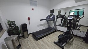 Ein Fitnessstudio mit Laufband, Crosstrainer und Wasserspender.