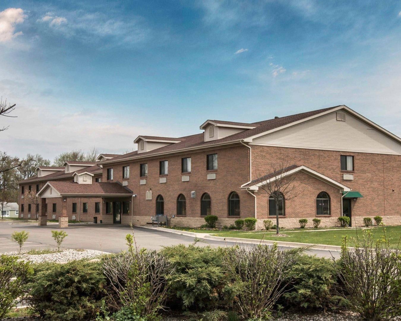 A multi-story brick building with a covered entrance and a parking lot in front.