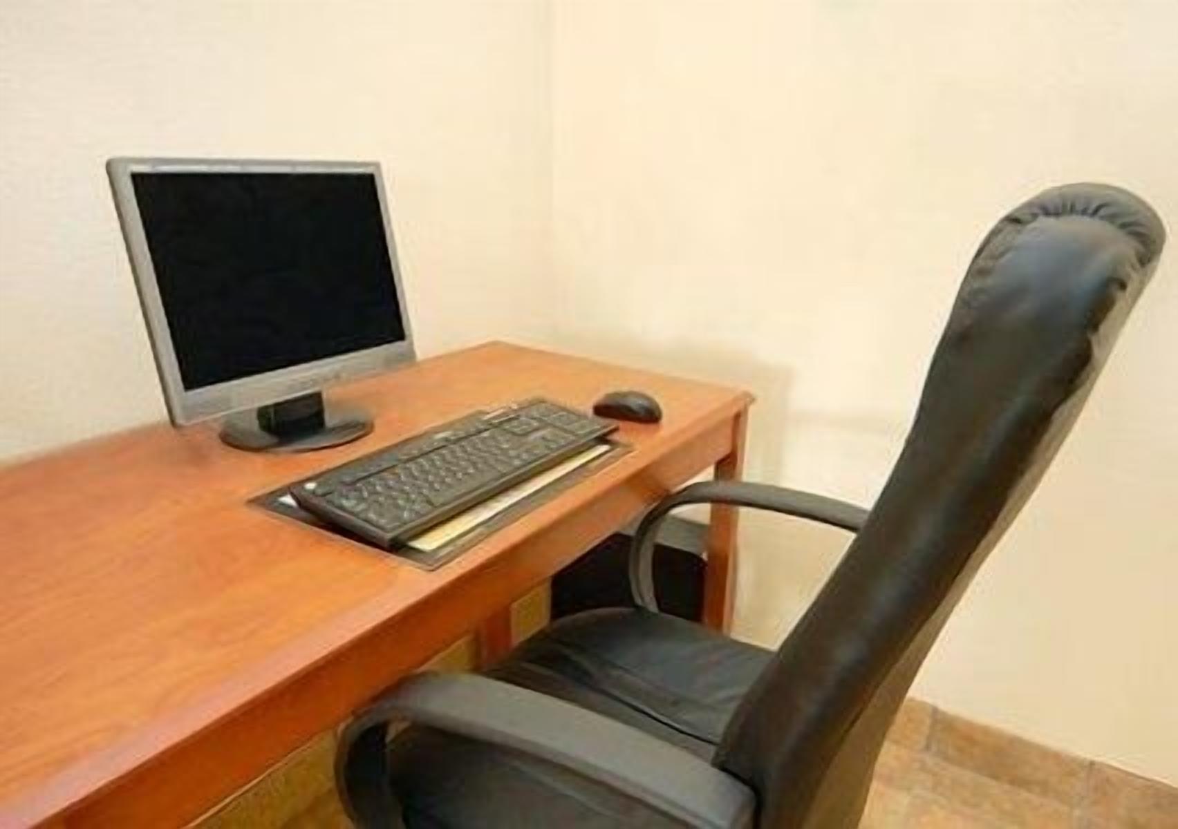 A wooden desk with a computer monitor, keyboard, and mouse.