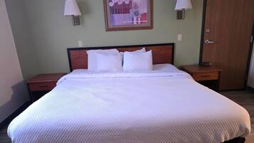 A neatly made bed with white bedding, two bedside tables with lamps, and a framed artwork on the wall.