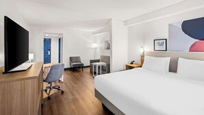 A hotel room with a large bed, a desk with a computer, a chair, a small table, and a TV. - Spark by Hilton Woodbridge (Woodbridge)